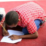 man in red and white plaid button up shirt writing on white paper