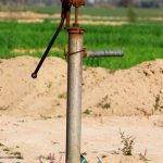 a pipe sticking out of the sand with a green field in the background
