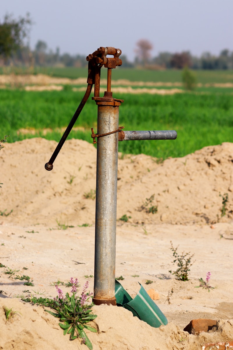 a pipe sticking out of the sand with a green field in the background